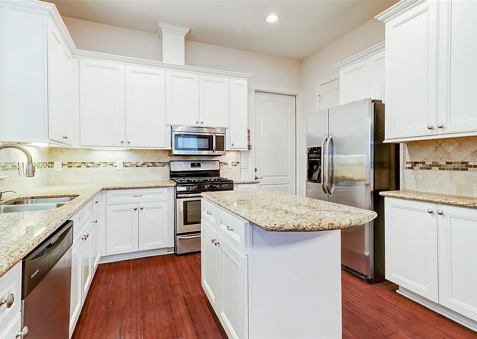 Light and bright kitchen with granite countertops, stainless steel appliances, walk-in pantry and island.