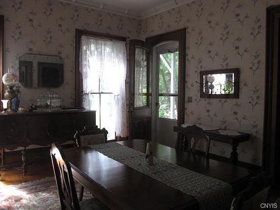 Inside now, from the porch to the dining room.  Notice the long window, the wood under the carpet, the molding on the high ceiling.  The mirror reflects another window - that's how large this room is!  To the right is the living room.