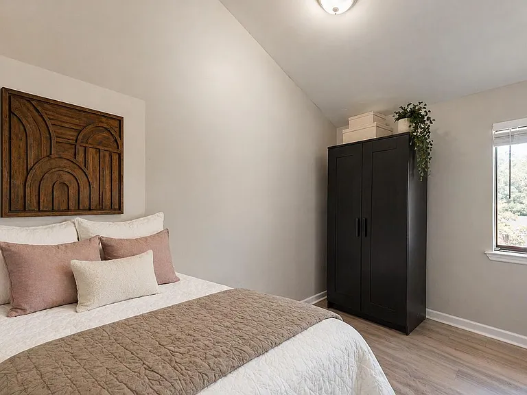 Well-sized bedroom with a full bed setup, roomy wardrobe storage, and a large window for natural light and neighborhood views