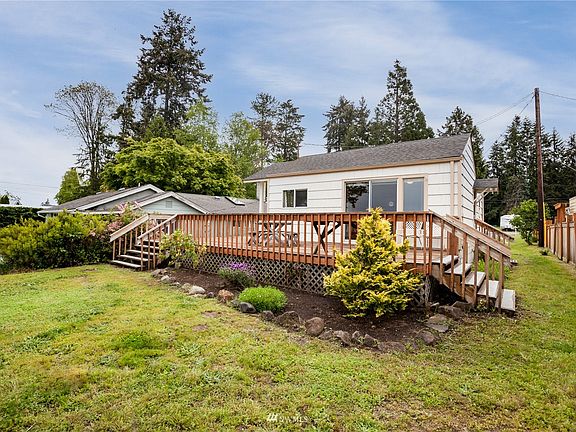 The front side of the house facing the water; there's an attached wrap-around deck accessible both from the house and from two points from the yard.>