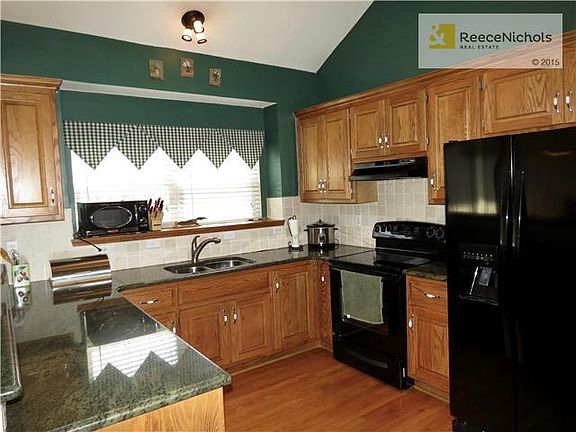 Functional Kitchen with Granite Counter Tops & Black Appliances.