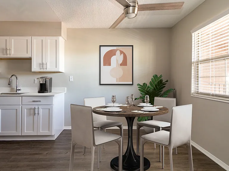 Renovated kitchen with white cabinetry, laminate countertop, and wood-style plank flooring
