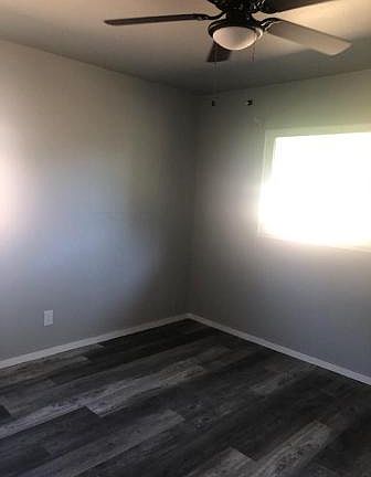 Master bedroom with two windows , same new light fan and laminate floor.