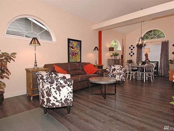 Living room with hardy laminate floors, vaulted ceilings and plenty of natural light. In the distance you can see the dining room.