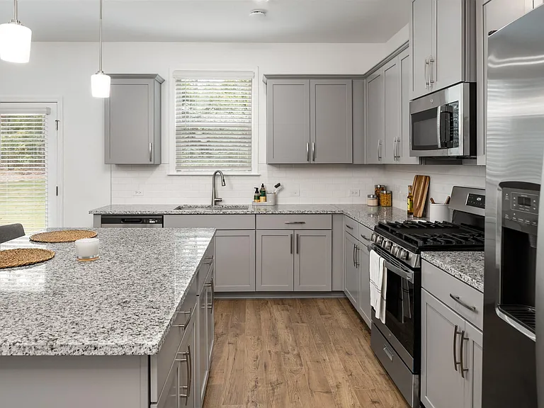 Spacious kitchen with an island, ample storage, stainless steel appliances and view into the living room.