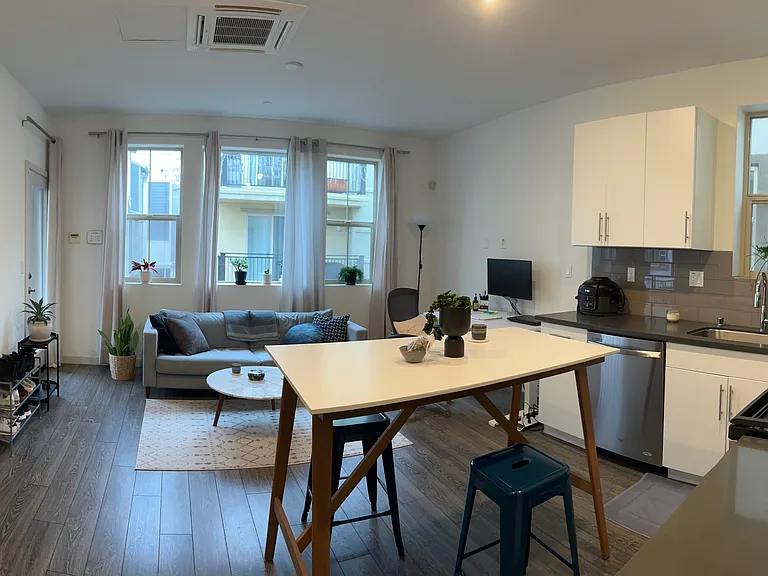 View from bedroom space into living room area and kitchen space (decorated)
