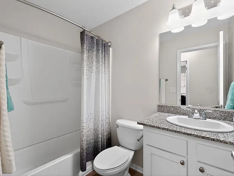 Contemporary bathroom with elegant granite countertop, chic lighting, and modern bathtub featuring a stylish shower curtain. Contemporary bathroom with elegant granite countertop, chic lighting, and modern bathtub featuring a stylish shower curtain.