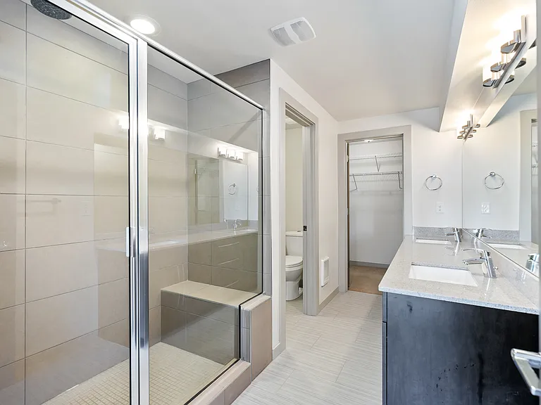 Primary en-suite has spacious shower with sitting bench, dual sink vanity and Quartz countertops.