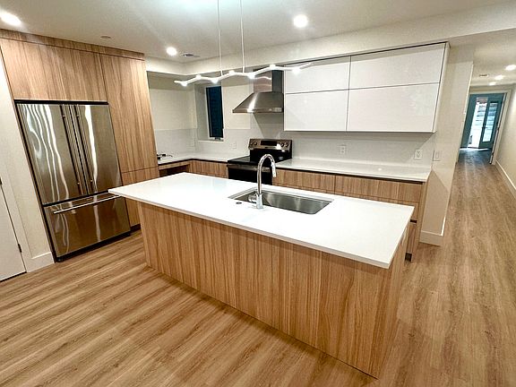 Kitchen with three door refrigerator, electric stove, ample cabinetry storage, counter space, and island