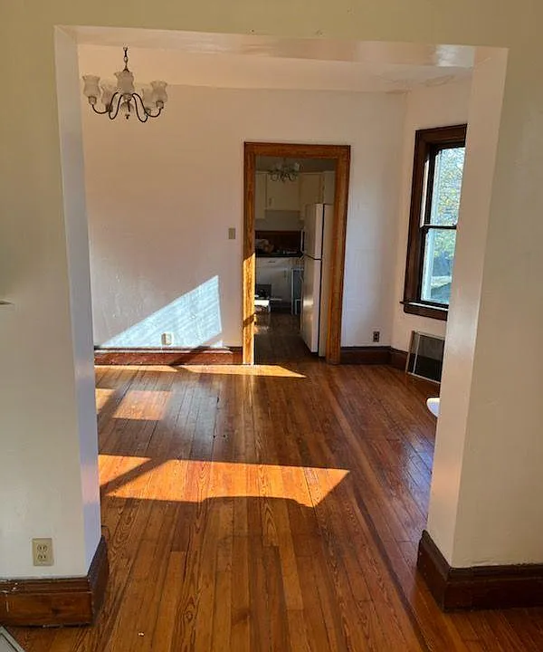 dining room view from living room, and towards the kitchen; dining room has 3 south facing windows, lovely wooden floors and a cute chandelier