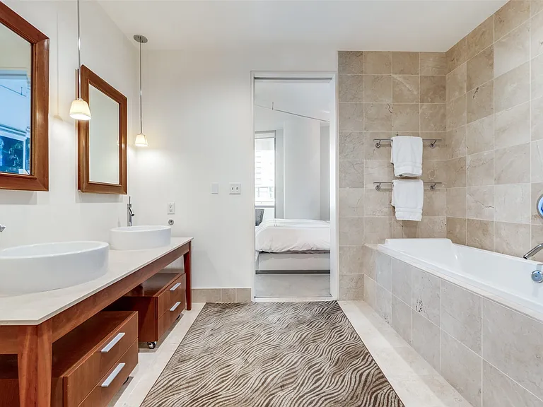 Bathroom featuring connected bathroom, light tile patterned flooring, double vanity, and a relaxing tiled tub