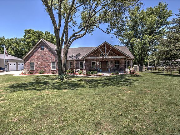 View of the front of the home & shop. Large corner lot on 1 ac with mature trees.