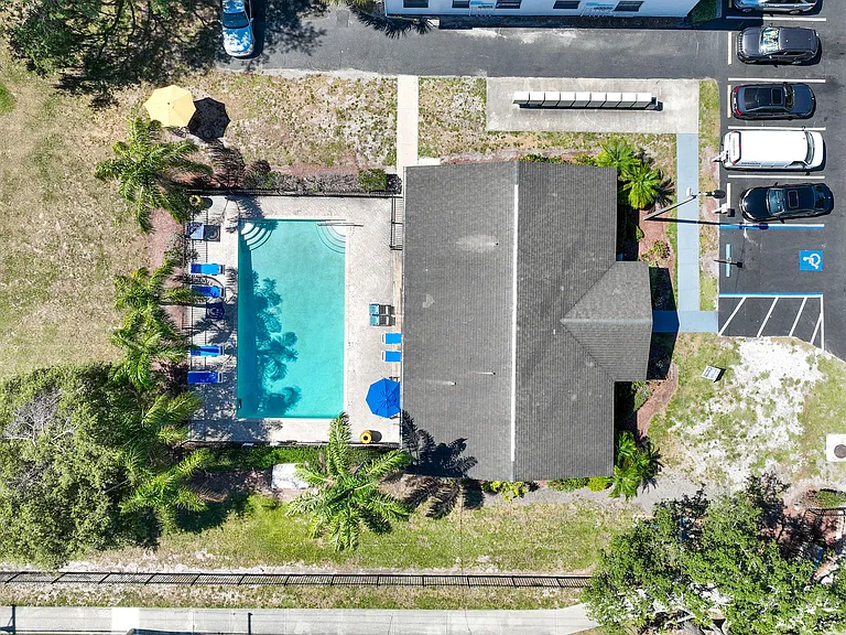 Inviting aerial view of a luxurious apartment complex with a sparkling outdoor pool, surrounded by lush greenery and convenient parking.