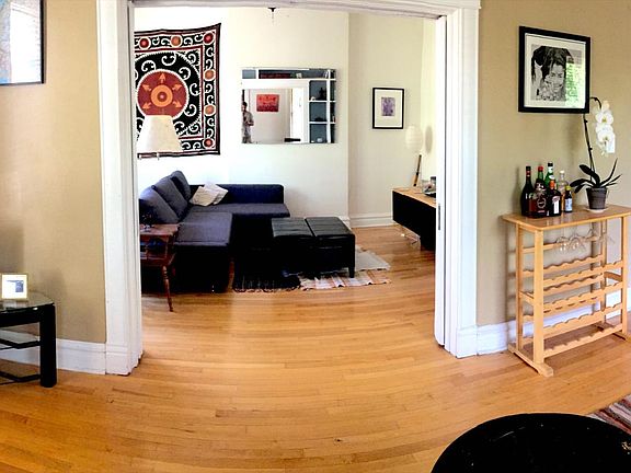 Large main room, looking through double pocket doors (fully closable) into bedroom 1 (currently staged as a den with sofa).
