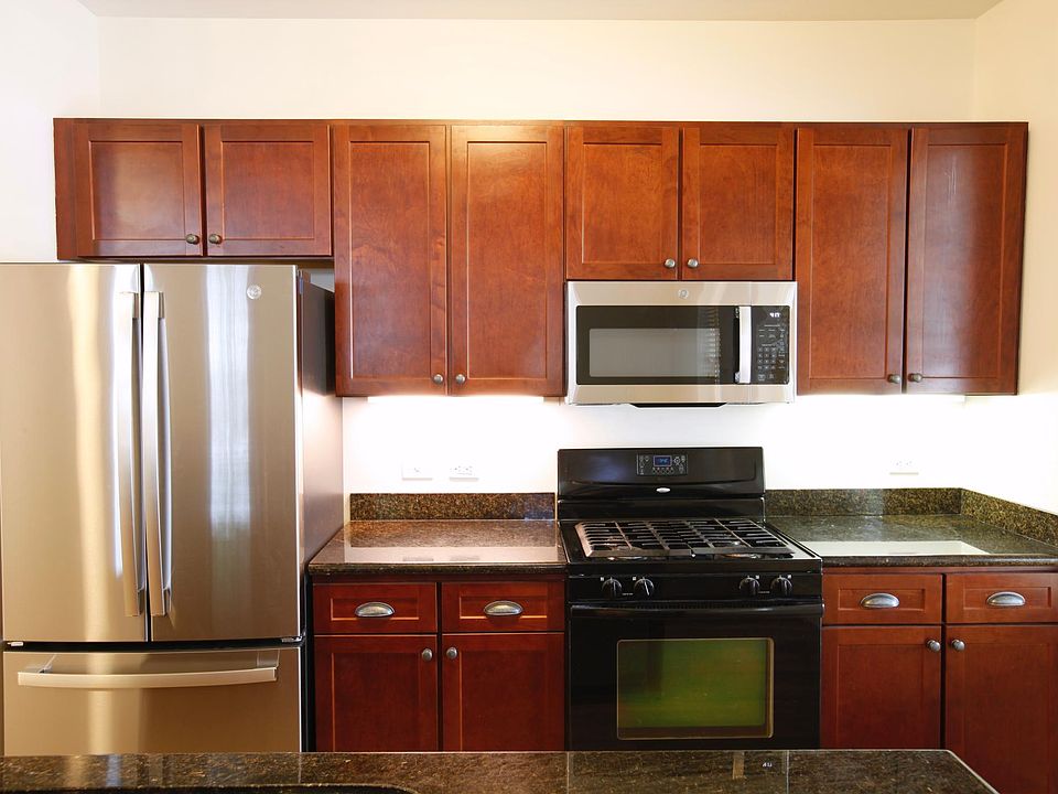 Full view of new stainless front refrigerator with microwave, range and extensive cabinets