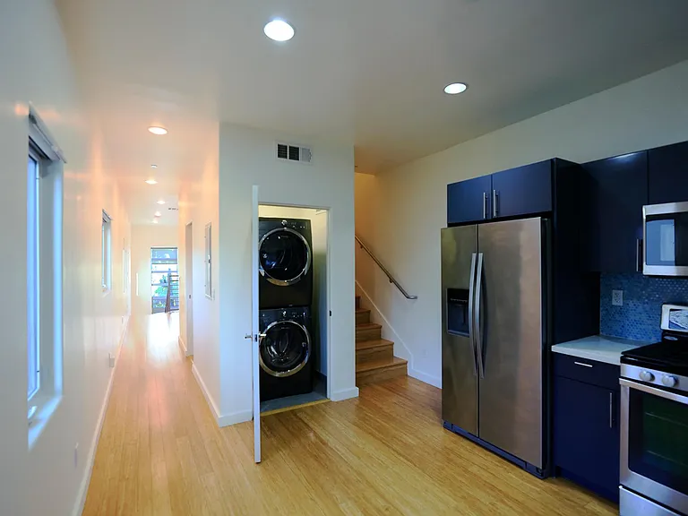 Laundry Closet in Kitchen with Hallway Leading to Guest Bathroom and Living Room and Staircase Leading to Upstairs Bedrooms
