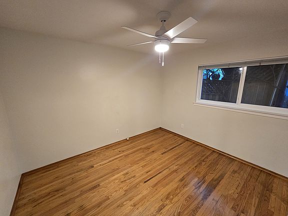 Bedroom has hardwood floors, ceiling fan and full length mirrors.