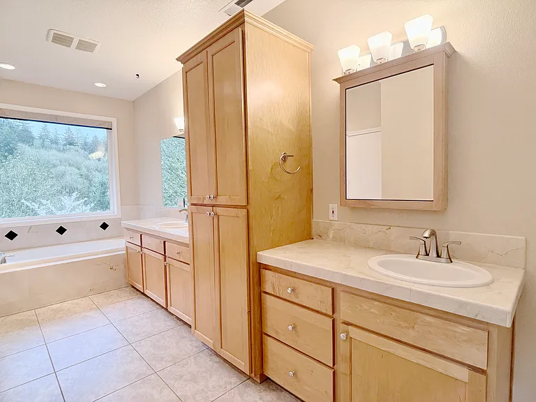 Elegant en suite bathroom featuring a heated floor, dual vanities with enhanced privacy, an oversized soaking tub, a walk-in shower with dual showerheads, and a secluded toilet area.