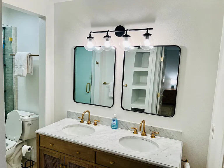 Double sinks in the primary bathroom. Walk in closet to the right, commode and shower to the left