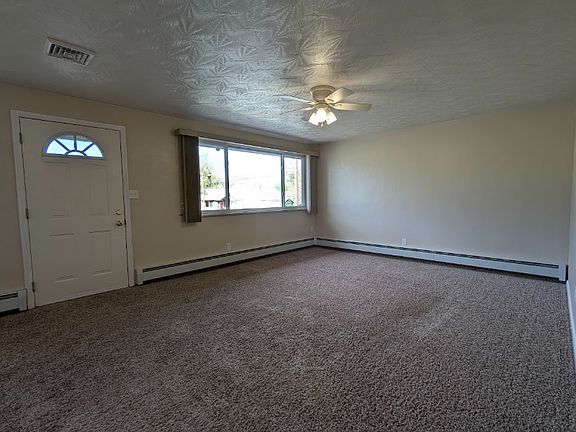 Large living room with fancy ceilings, a ceiling fan, and central air conditioning