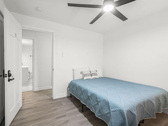 Standard room w/ queen bed, writing table, mini fridge, ceiling fan.