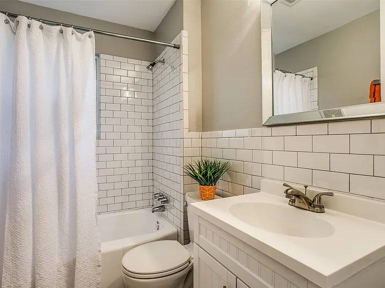 Bathroom featuring a white subway tile surround, white bathtub, and a white vanity with an integrated sink