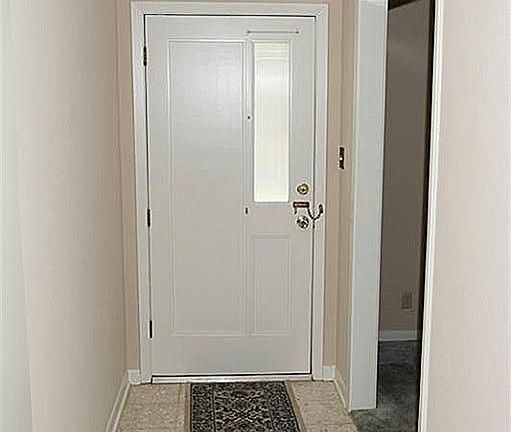 The front door opens to tile flooring. the door is solid but features a unique vertical window allow