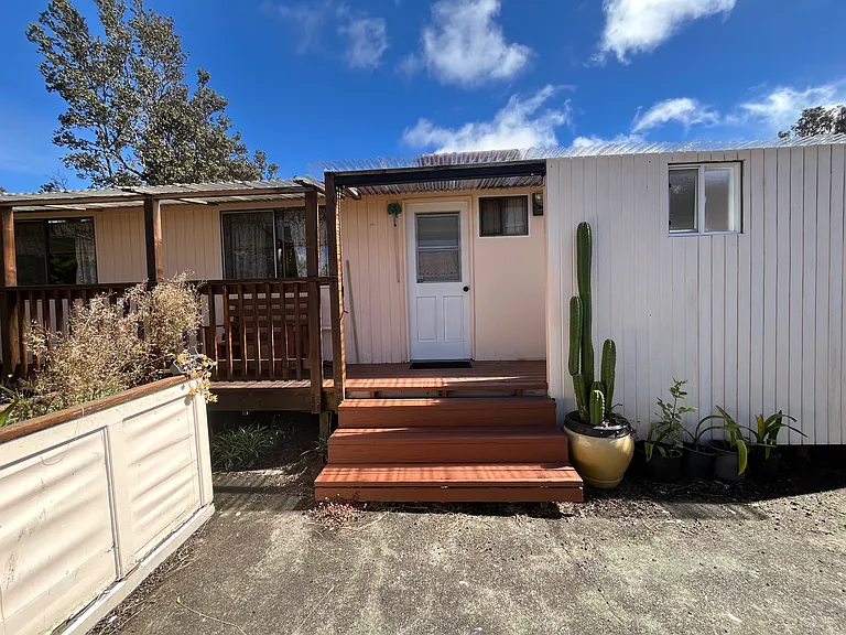 Side entrance with outdoor shower room on right and wrap-around deck to the left. Plant flowers in the tall garden bed on the left or watch dormant bulbs bloom.