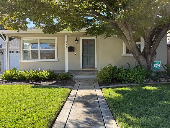 The entry features a covered patio with slate tile and a charming Japanese maple, creating a welcoming and picturesque first impression.