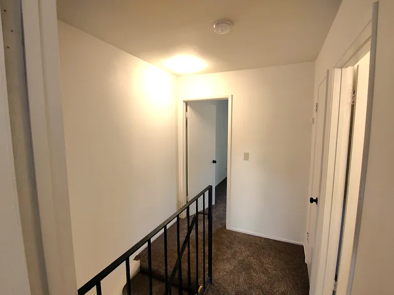 Upstairs hallway, as seen from the doorway of the 2nd bedroom. Bath is to the immediate right, primary bedroom is opposite.