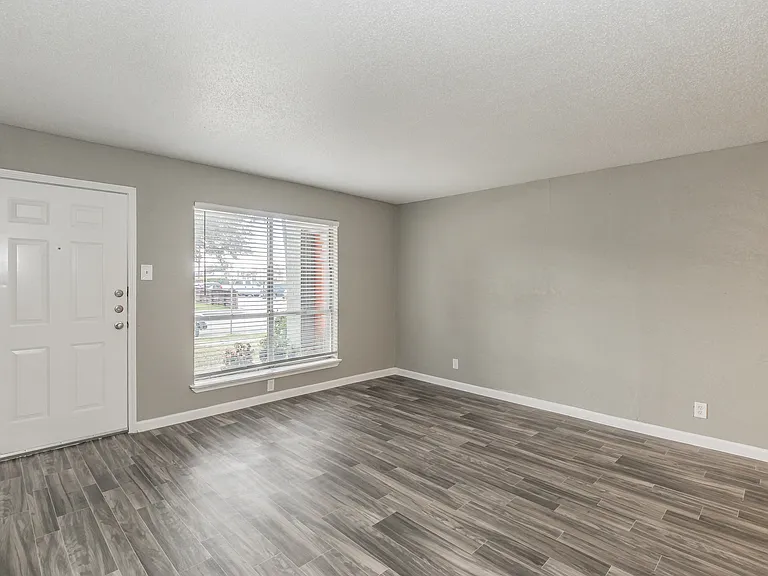 Spacious living areas feature natural light and wood-style flooring at Chapel Creek Apartments.