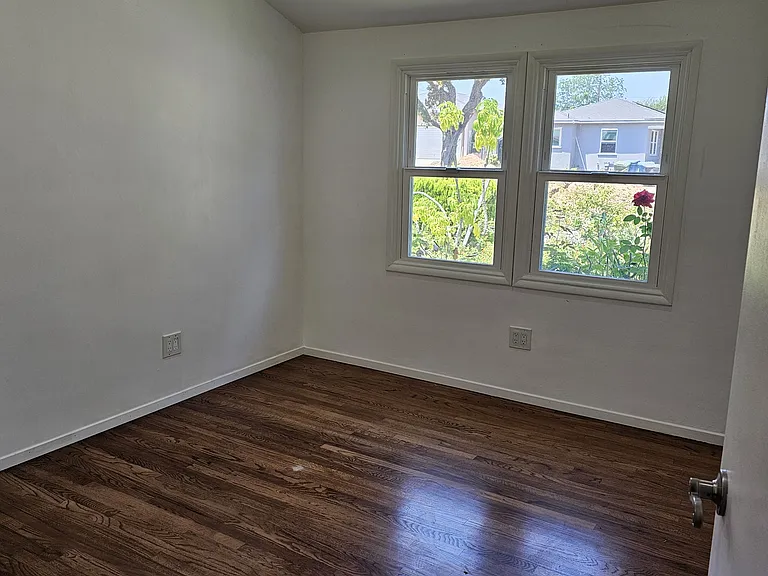 Bedroom, highlighting windows and hardwood floor.