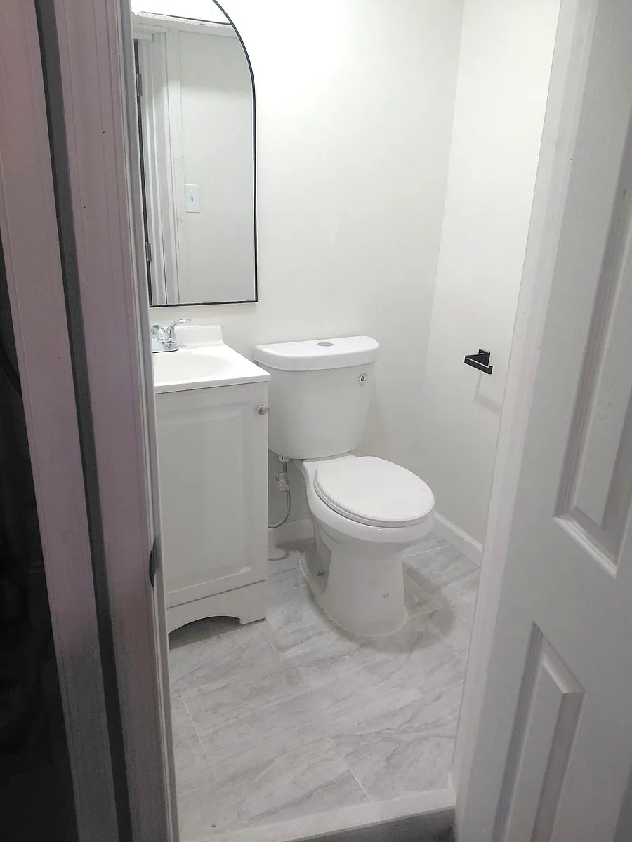 Compact half-bath with a single-sink vanity, framed mirror, and easy-clean tile flooring for everyday convenience. - Saber St