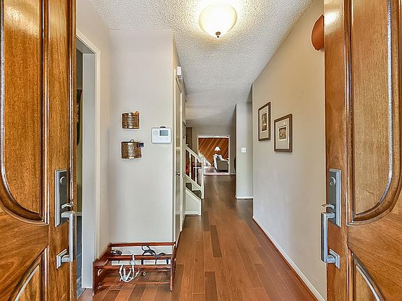 From the Entry, towards the rear of the house and the gorgeous Den, with the vaulted ceiling, built in display cabinets, vertical wood accent wall,wet bar, and window seating. Rectified wood look Porcelain tile flooring. Gorgeous!