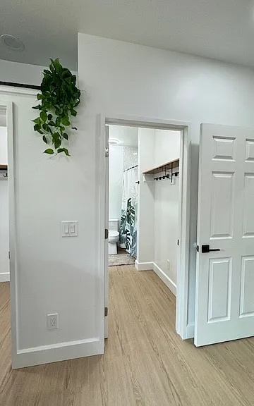 Primary bathroom's entrance with ample shelf and hanging space.