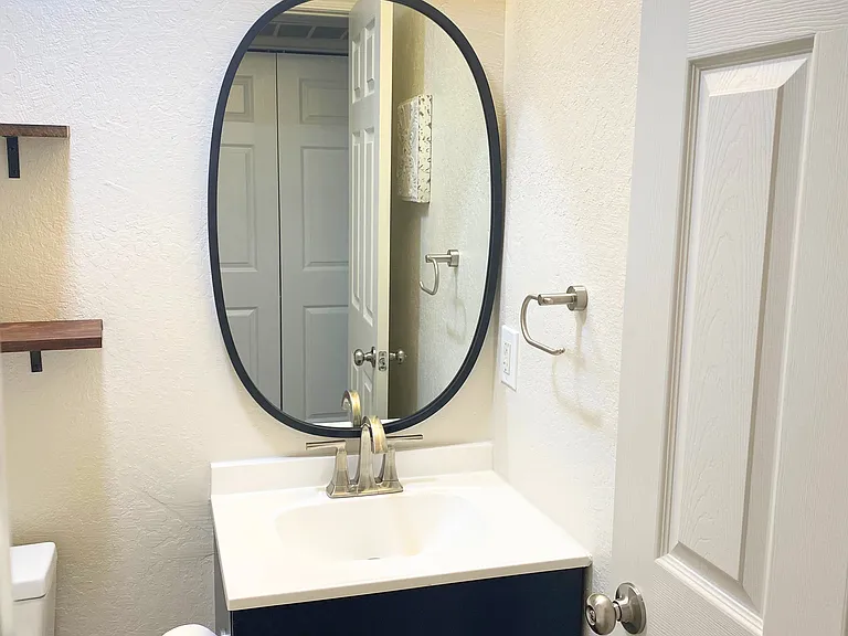 Hall Bathroom setup featuring a stylish sink, mirror, convenient shelves-perfect for your essentials.