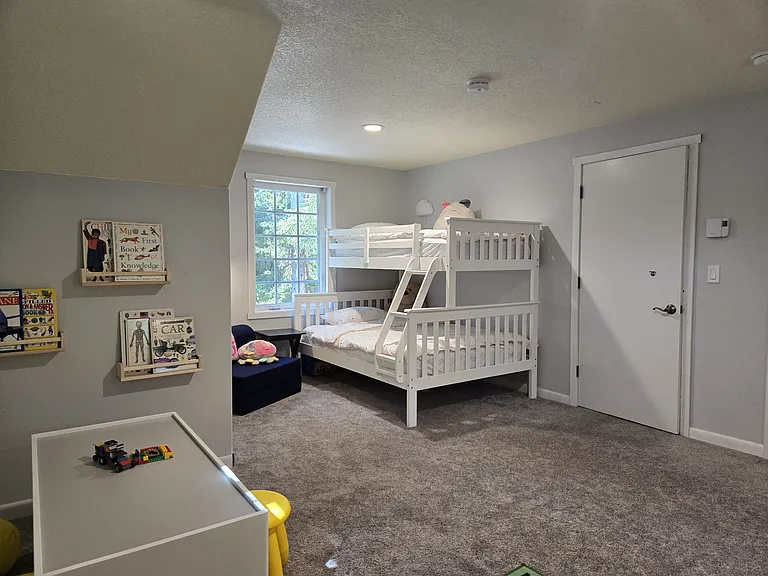 Second-floor kids bedroom with two bunkbeds, play area, toys, books, and a 50" TV