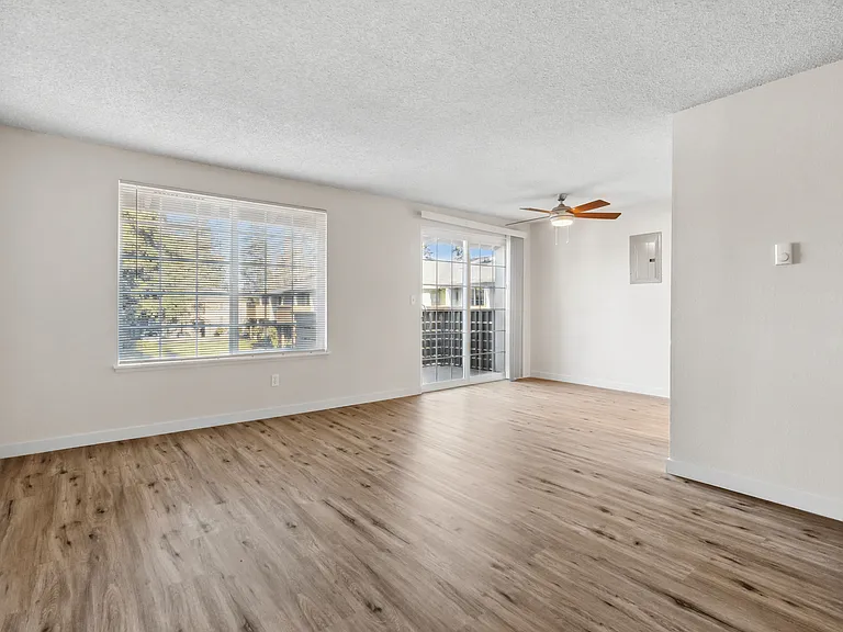 Experience comfort in this airy living room, featuring expansive windows and sleek hardwood flooring. Experience comfort in this airy living room, featuring expansive windows and sleek hardwood flooring.