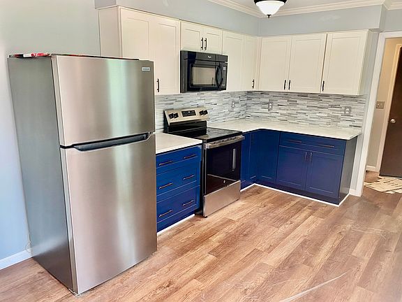 Kitchen with new fridge, oven and microwave. It has Laminate Vinyl Plank flooring.