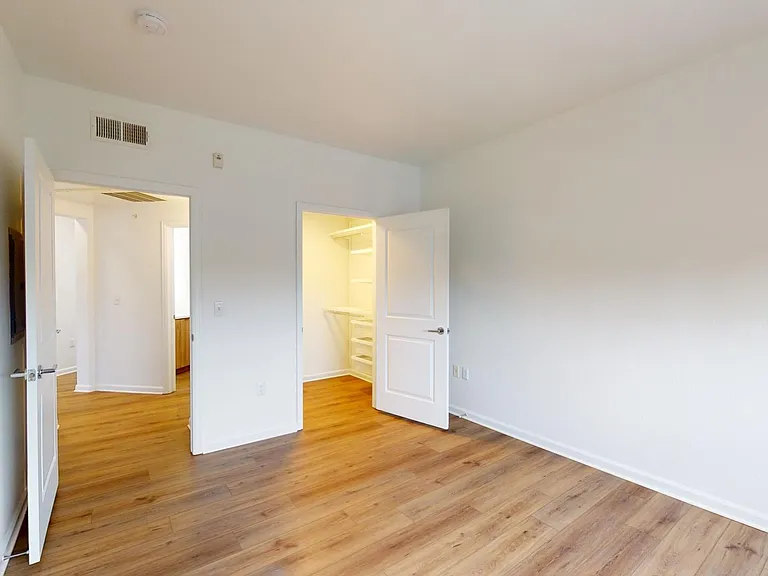 Spacious apartment bedroom with large closet and wood style floor.