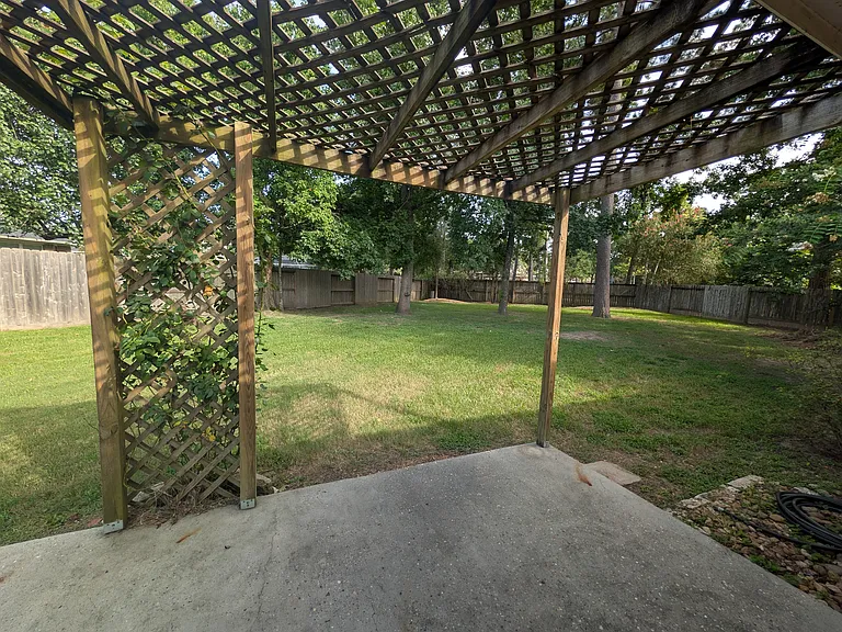 Additional outdoor entertaining area under a wooden pergola lattice, perfect for climbing vines or creating a cozy outdoor seating nook.