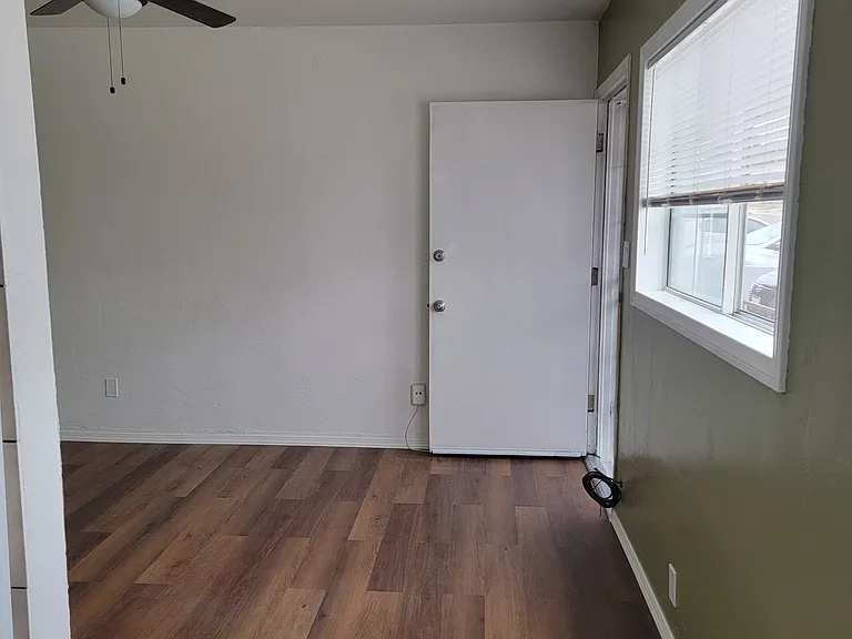 Walkway towards Living room with matcha accent painted wall and dark ceiling fan fixture.