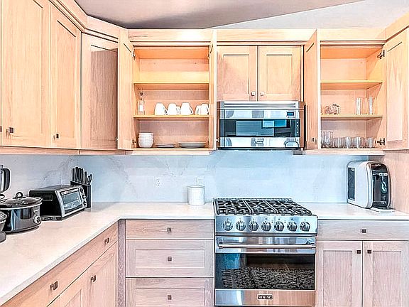 Kitchen detail showing ample cabinet storage, gas cooktop, and clean white quartz countertops