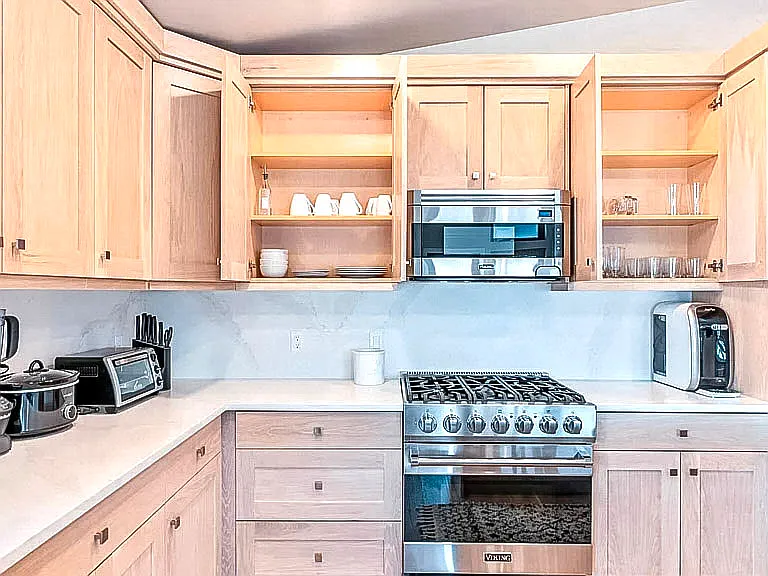 Kitchen detail showing ample cabinet storage, gas cooktop, and clean white quartz countertops