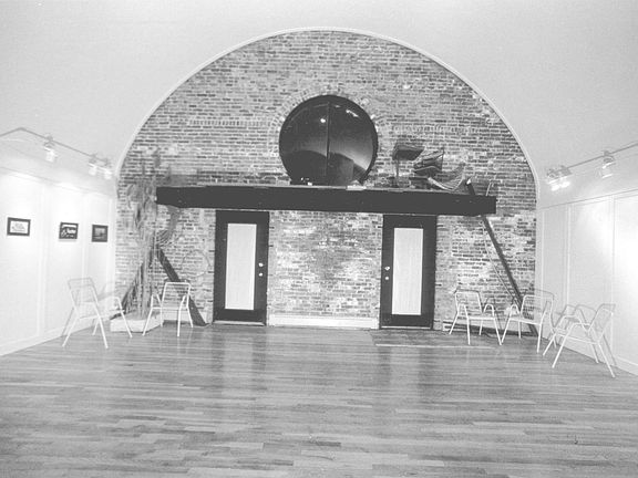 Unit's main interior space: 18' foot high vaulted ceiling, was part of historic temple. Doors with exposed masonry wall, lead to private deck.