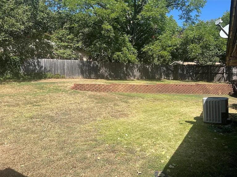 Expansive backyard featuring a retaining wall, wood privacy fencing, and mature trees