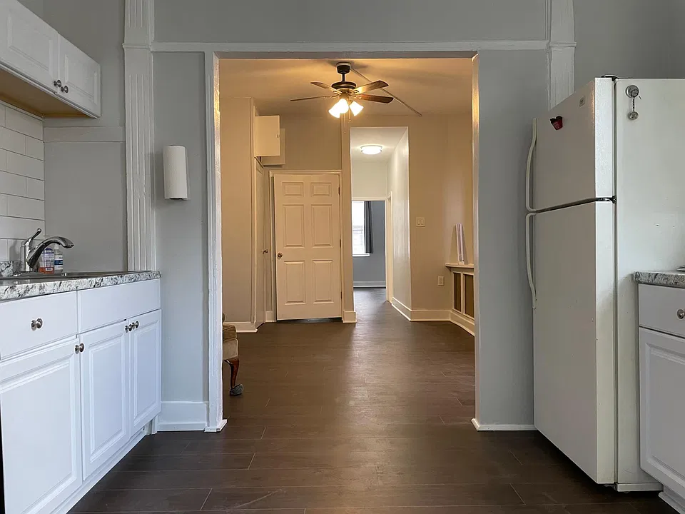 View from kitchen through living room down hallway into the bedroom at the far end of the photo