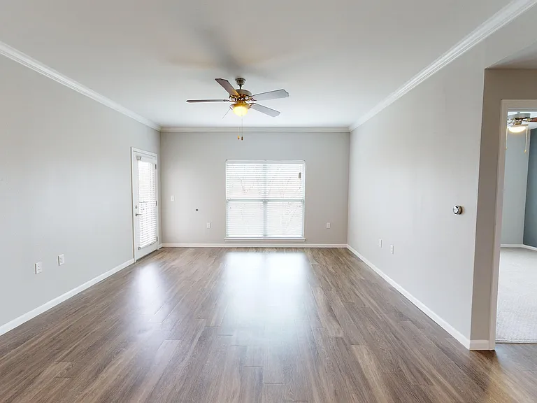 The Walnut floor plan features a large living room with wood-style flooring, natural light, and access to a private patio or balcony. The Walnut floor plan features a large living room with wood-style flooring, natural light, and access to a private patio