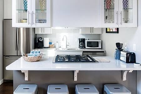 Modern kitchen adjacent to living area has stainless appliances and quartz countertops