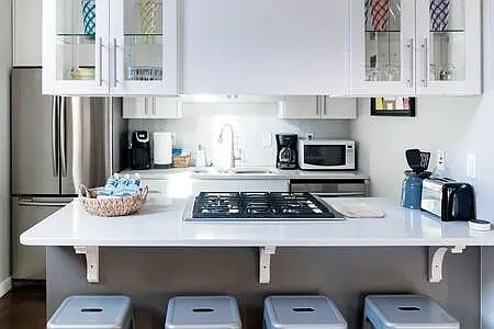 Modern kitchen adjacent to living area has stainless appliances and quartz countertops